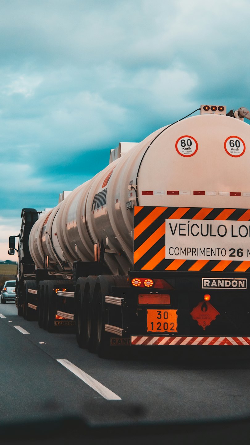 Tanker truck with flammable liquid warning signs on highway.