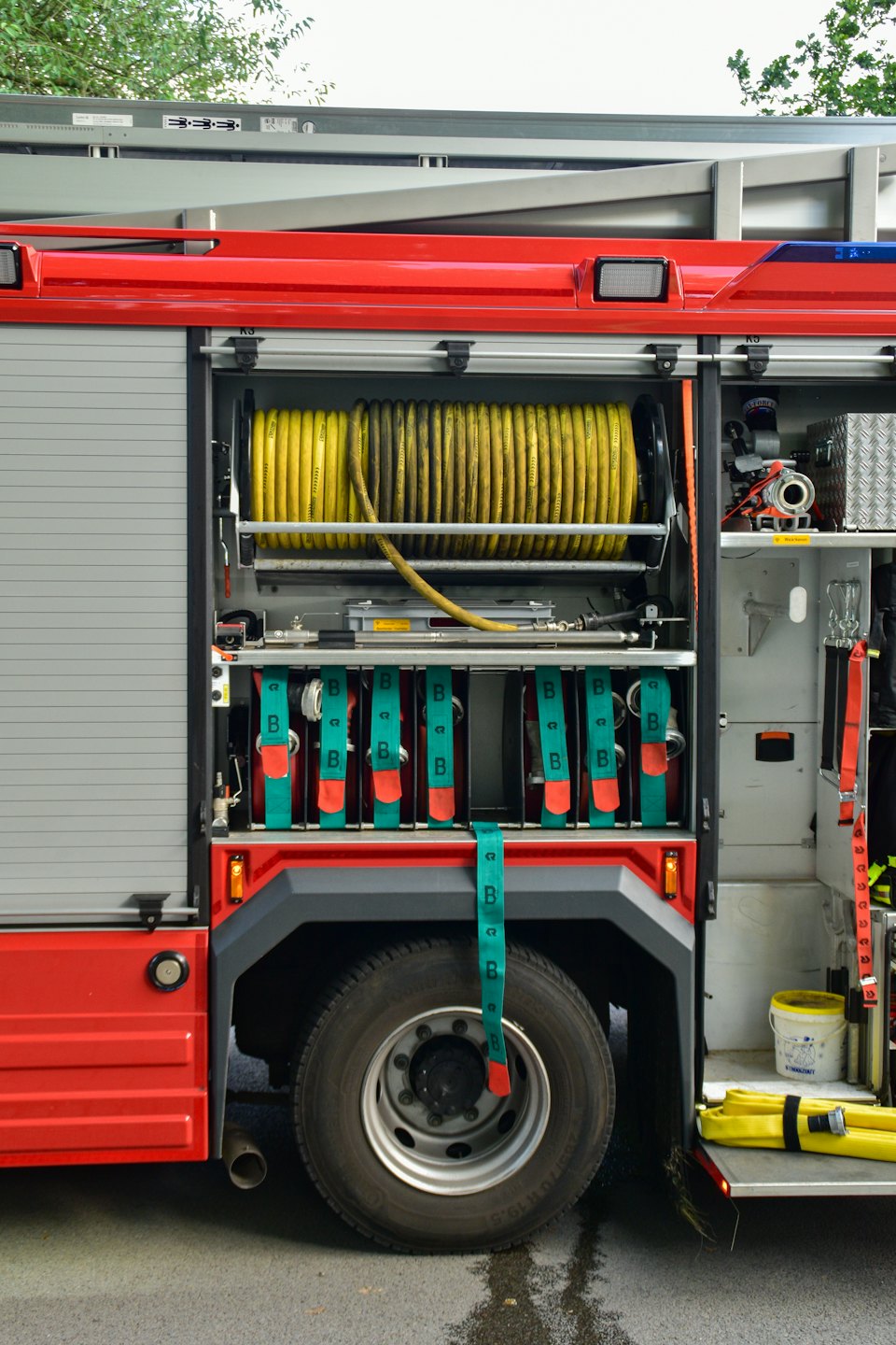 Coiled yellow hoses and tools inside a fire truck compartment.