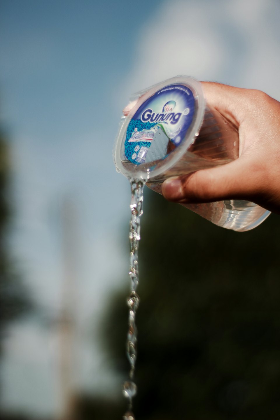 A hand pours water from a branded plastic cup.